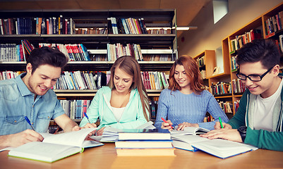 Image showing happy students writing to notebooks in library