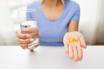 Image showing close up of woman hands with capsules and water