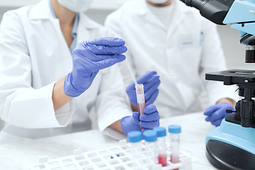 Image showing close up of scientists filling test tube in lab