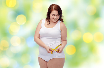 Image showing happy young plus size woman with measuring tape