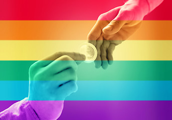 Image showing close up of male gay couple hands giving condom