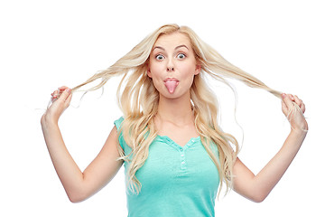 Image showing happy young woman showing tongue and holding hair