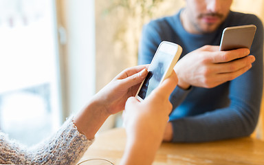 Image showing close up of couple with smartphones at cafe