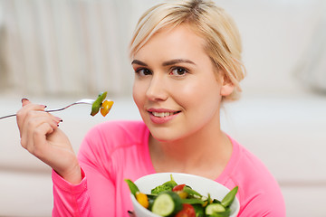 Image showing smiling young woman eating salad at home