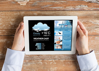 Image showing close up of hands with weather cast on tablet pc