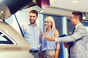 Image showing happy couple with car dealer in auto show or salon