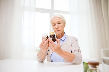 Image showing senior woman with medicine jars at home