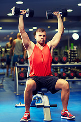 Image showing young man with dumbbells flexing muscles in gym