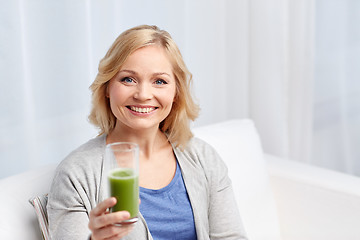 Image showing happy woman drinking green juice or shake at home