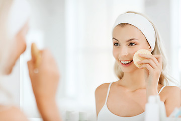 Image showing young woman washing face with sponge at bathroom