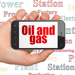 Image showing Industry concept: Hand Holding Smartphone with Oil and Gas on display