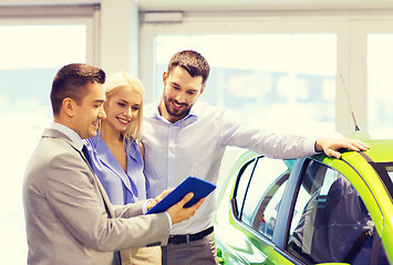 Image showing happy couple with car dealer in auto show or salon