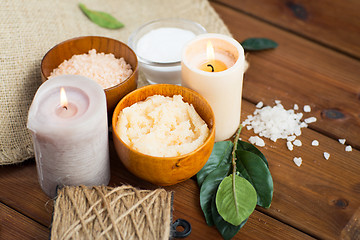 Image showing close up of natural body scrub and candles on wood