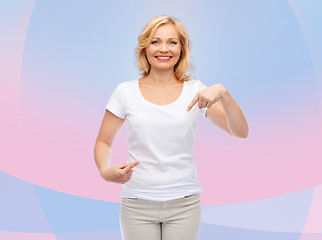 Image showing smiling woman in white t-shirt pointing to herself