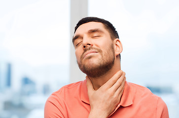 Image showing unhappy man suffering from throat pain at home