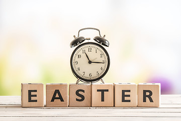 Image showing Alarm clock on a wooden easter sign