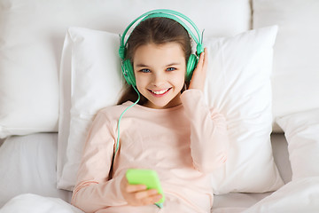 Image showing happy girl lying in bed with smartphone at home