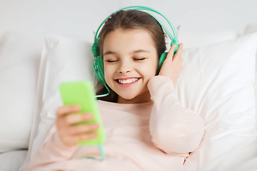 Image showing happy girl lying in bed with smartphone at home