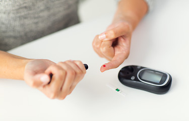 Image showing close up of woman making blood test by glucometer