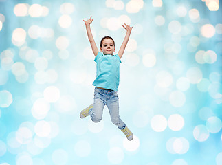 Image showing happy little girl jumping in air over blue lights