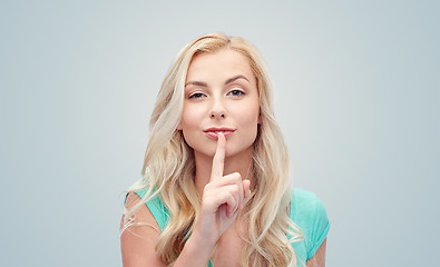 Image showing beautiful young woman holding finger at her lips