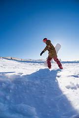 Image showing Snowboarder walking against blue sky