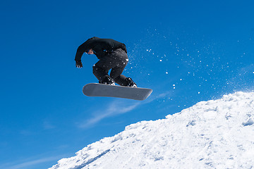 Image showing Snowboarder jumping against blue sky