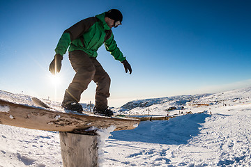 Image showing Snowboarder sliding on a rail