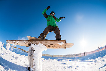 Image showing Snowboarder sliding on a rail