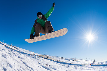 Image showing Snowboarder jumping against blue sky