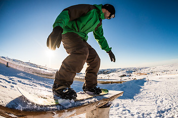 Image showing Snowboarder sliding on a rail