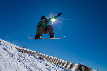 Image showing Snowboarder jumping against blue sky