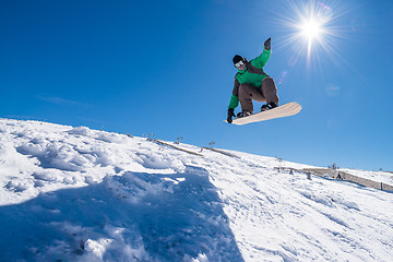 Image showing Snowboarder jumping against blue sky