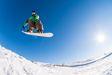 Image showing Snowboarder jumping against blue sky