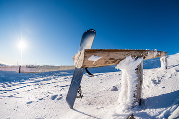 Image showing Snowboard leaning on a wood rail