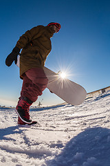 Image showing Snowboarder walking against blue sky