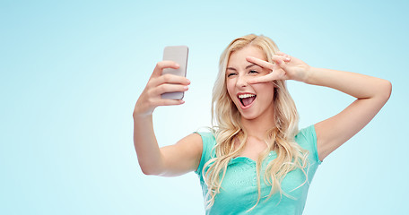 Image showing smiling young woman taking selfie with smartphone