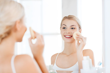 Image showing young woman washing face with sponge at bathroom