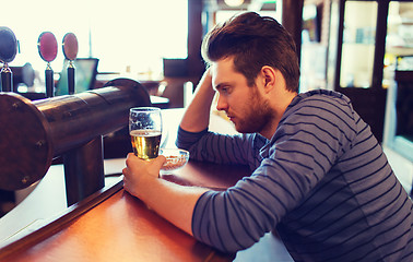 Image showing unhappy lonely man drinking beer at bar or pub