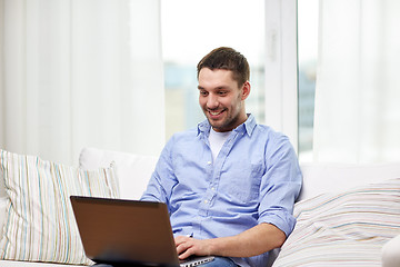 Image showing smiling man working with laptop at home