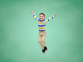 Image showing happy little boy jumping in air over school board