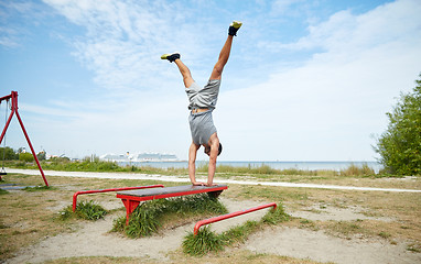 Image showing young man exercising on bench outdoors