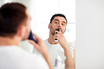 Image showing man shaving mustache with trimmer at bathroom