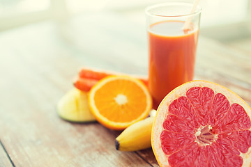 Image showing close up of fresh juice glass and fruits on table