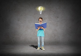 Image showing happy little girl in eyeglasses reading book