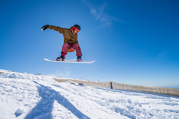 Image showing Snowboarder jumping against blue sky