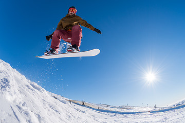 Image showing Snowboarder jumping against blue sky