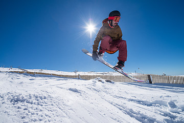 Image showing Snowboarder jumping against blue sky