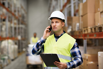 Image showing man with clipboard and smartphone at warehouse