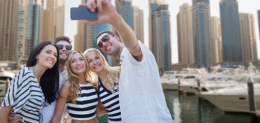 Image showing happy friends taking selfie over city harbor